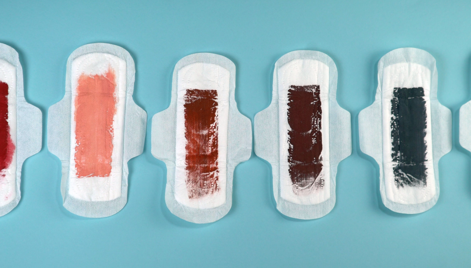 Period pads painted in different colours to visually represent types of vaginal discharge — supporting blog on discharge colour meanings and vaginal health.