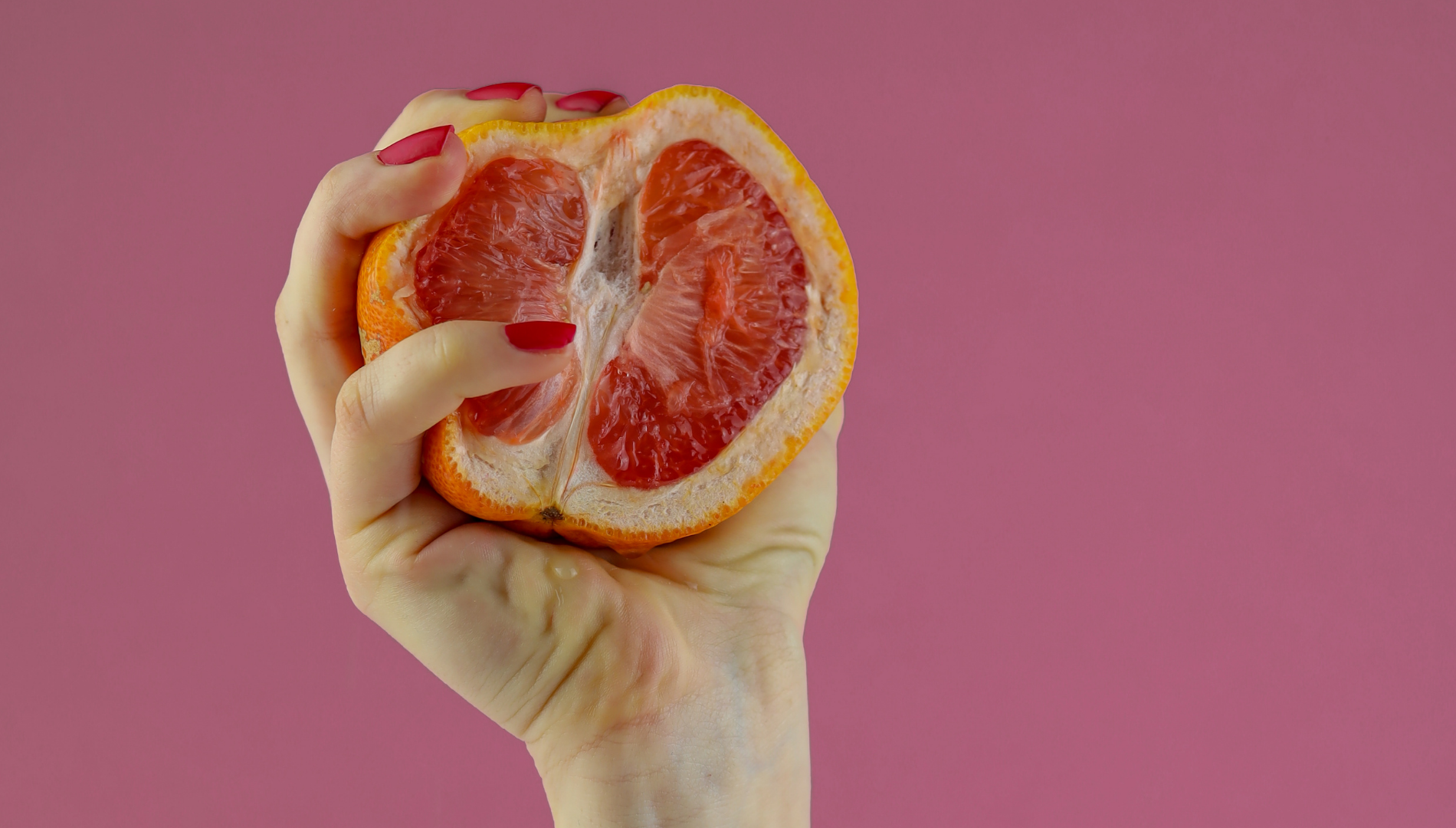 Hand holding a halved grapefruit symbolising vaginal health and yeast infections — supporting blog about thrush, antibiotics and vaginal care.