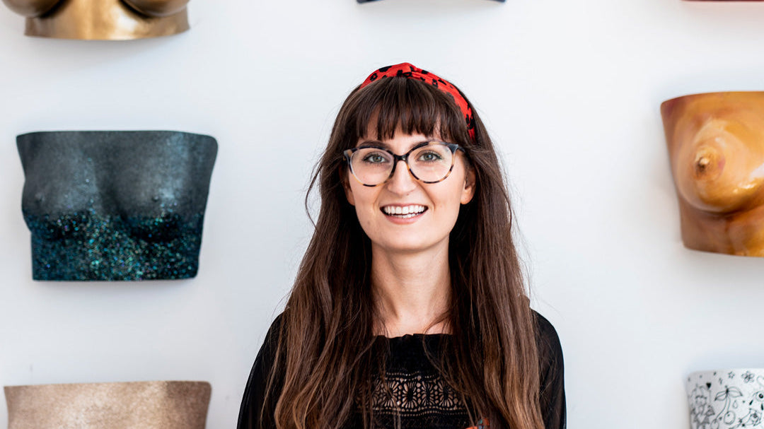 Artist in front of a wall of her body casting work.