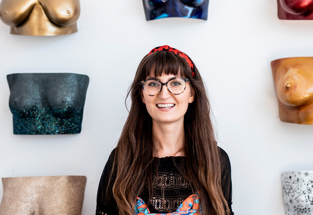 Artist in front of a wall of her body casting work.
