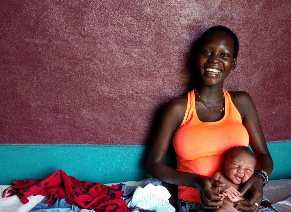 Happy Ugandan mother holding child.