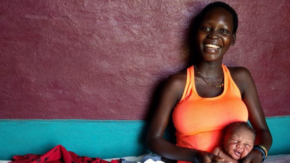 Happy Ugandan mother holding child.