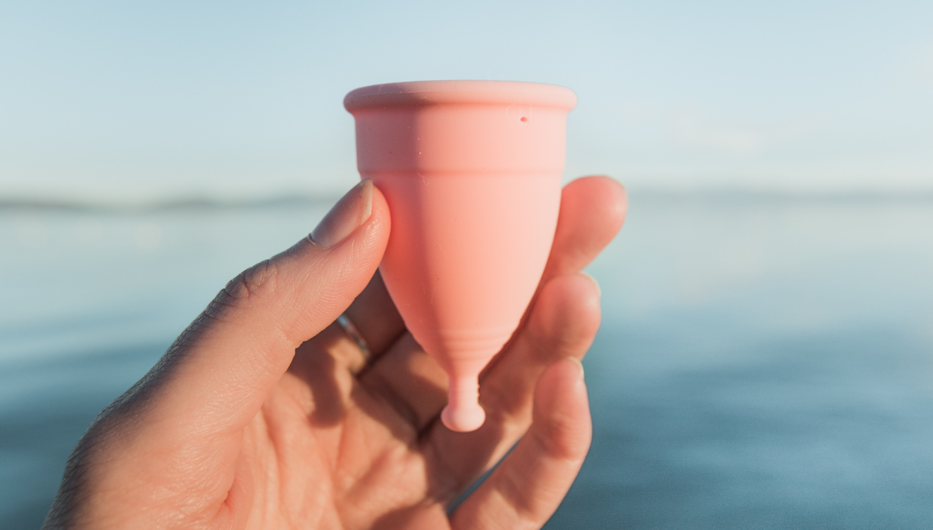 Mooncup menstrual cup shown with flexible base and stem, designed for easy, hygienic removal after use