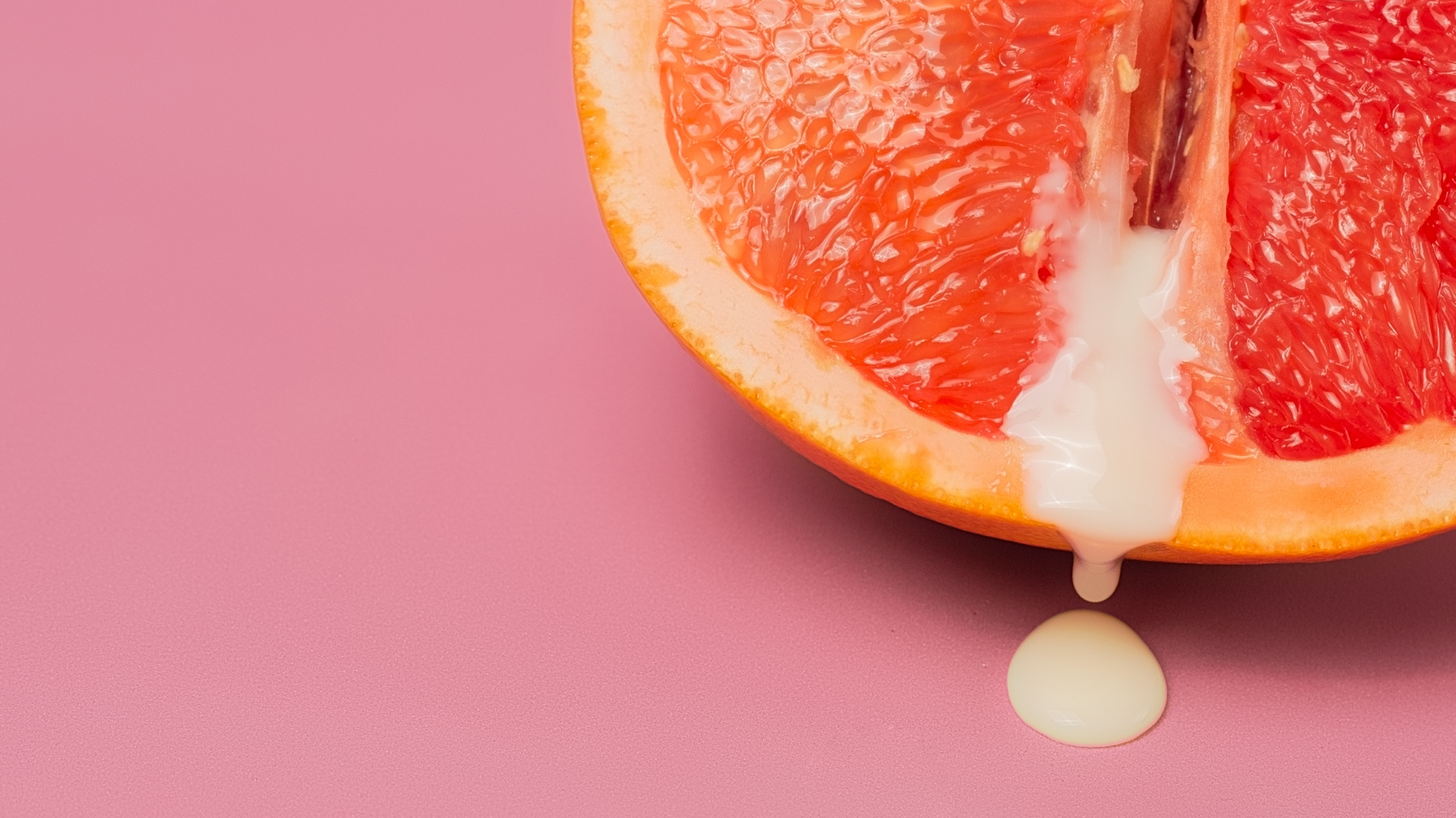 A halved grapefruit with white liquid — a symbolic representation of vaginal discharge, highlighting natural variations like pink discharge and what they may mean