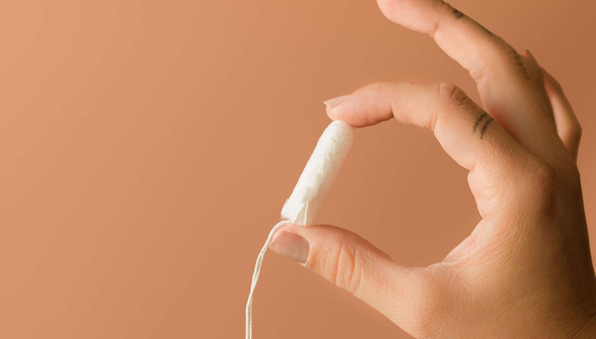Close-up of a hand holding a tampon — exploring the safety, myths, and tips for using tampons with an IUD in this menstrual health guide