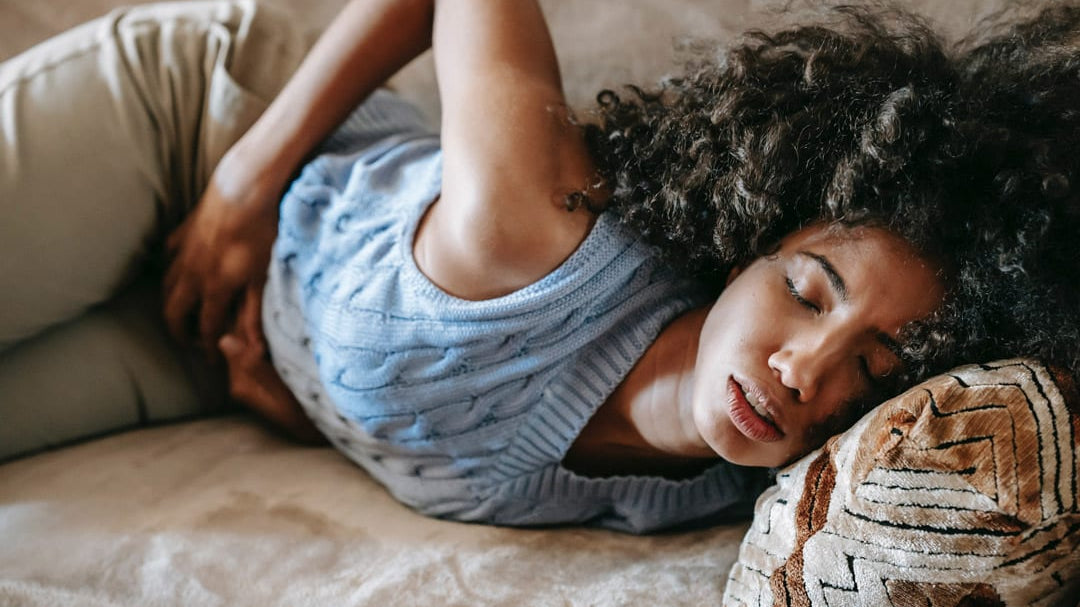 Woman lying on a sofa holding her stomach.