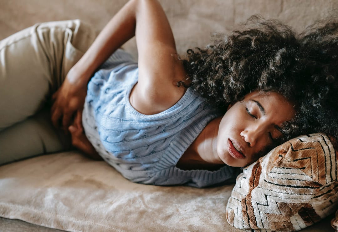 Woman lying on a sofa holding her stomach.