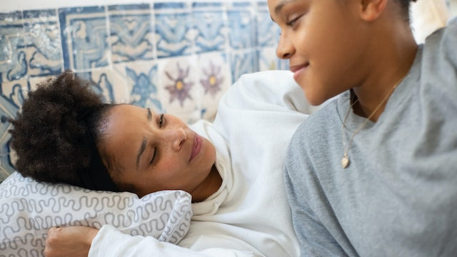 A mother and teen sat in a bed together.