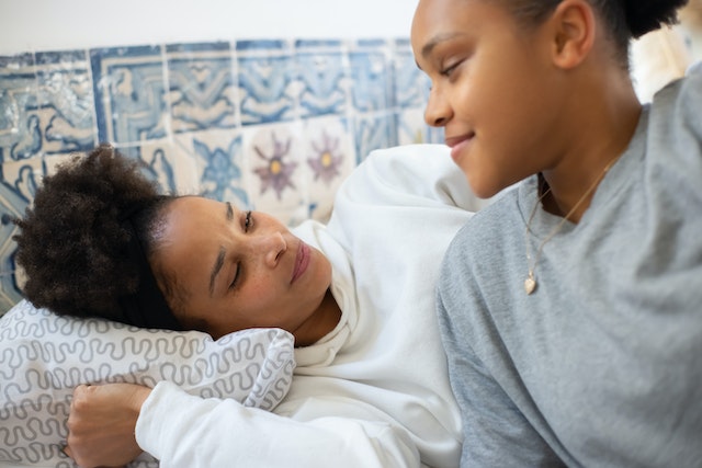 A mother and teen sat in a bed together.