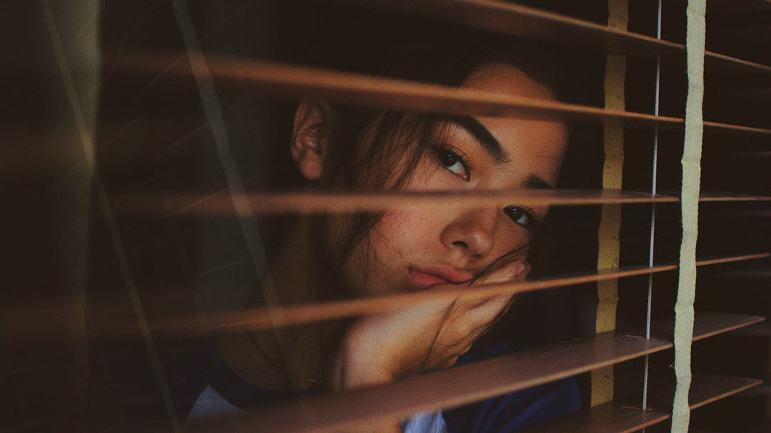 Girl looking out of blinds.