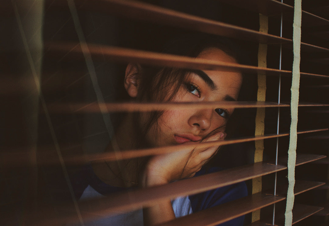 Girl looking out of blinds.